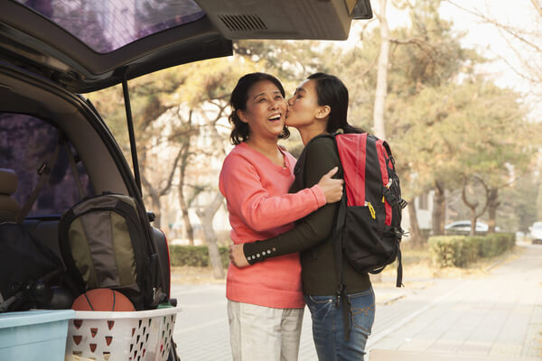 A mother and daughter hugging as daughter is dropped off at college.
