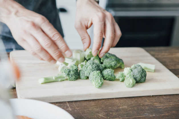 Broccoli on cutting board, with hands 