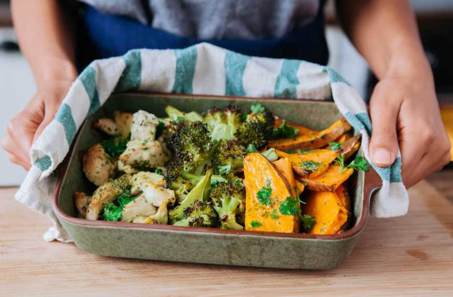 One pan roasted chicken sweet potato broccoli with hands 