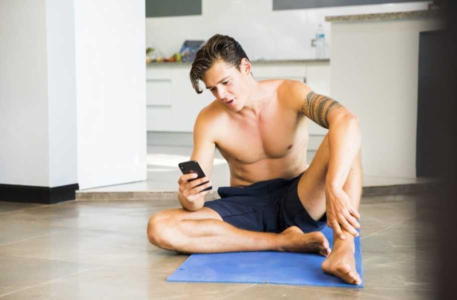 Shirtless man sitting on floor and looking at food