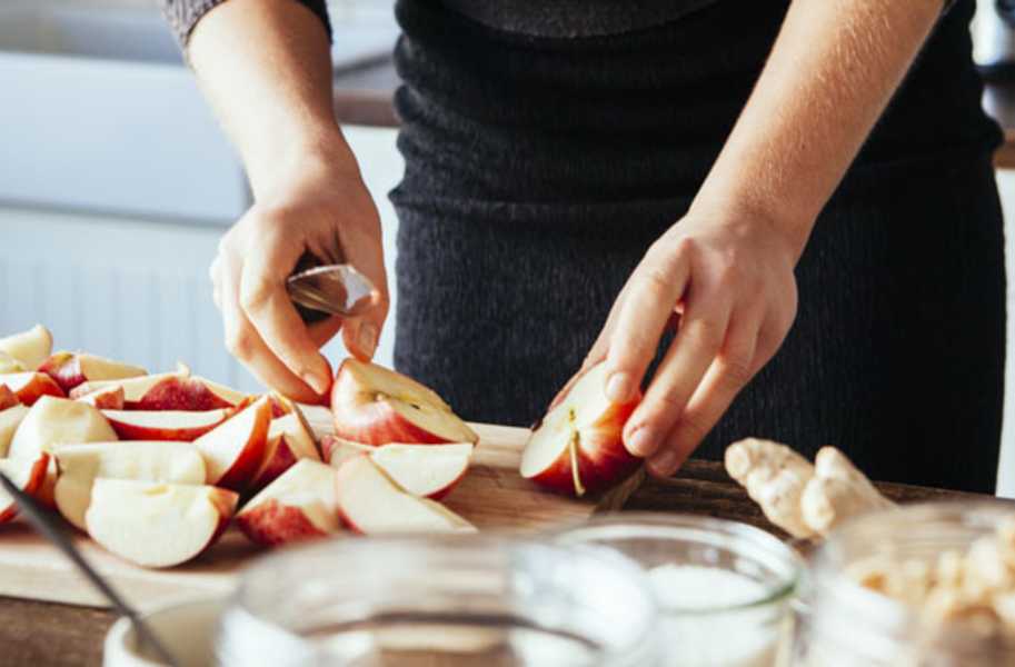 person slicing apples on a chopping board