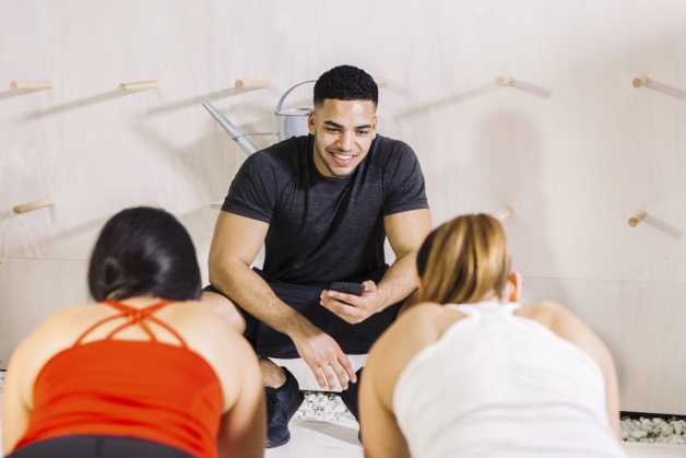 male with smartphone with two ladies planking 