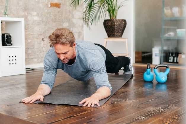 Tor, man, doing a plank, indoors and looking serious