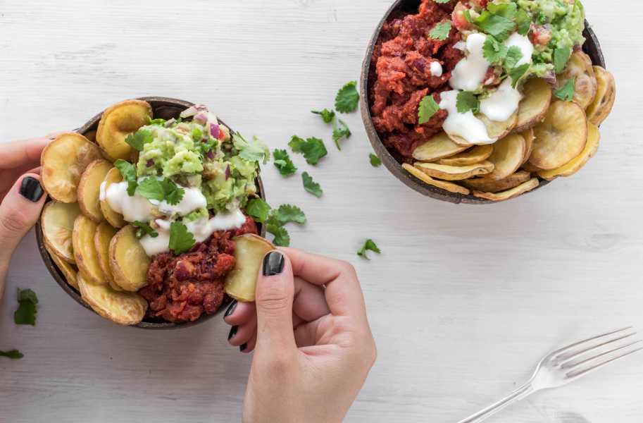 Woman eating a bowl of potato, avocado and chili