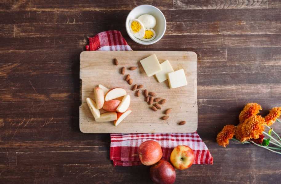 Breakfast  on the go, chopping board with apple, cheese, egg and almonds 