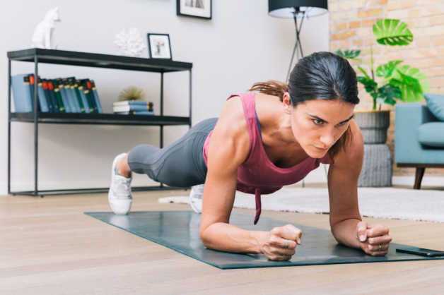 female planking on yoga mat in living room