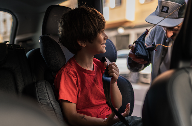 Child smiling at father while sat inside Volvo car