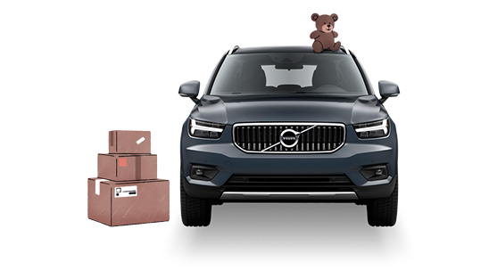 Teddybjörn ovanpå en Volvo bil bredvid flyttlådor