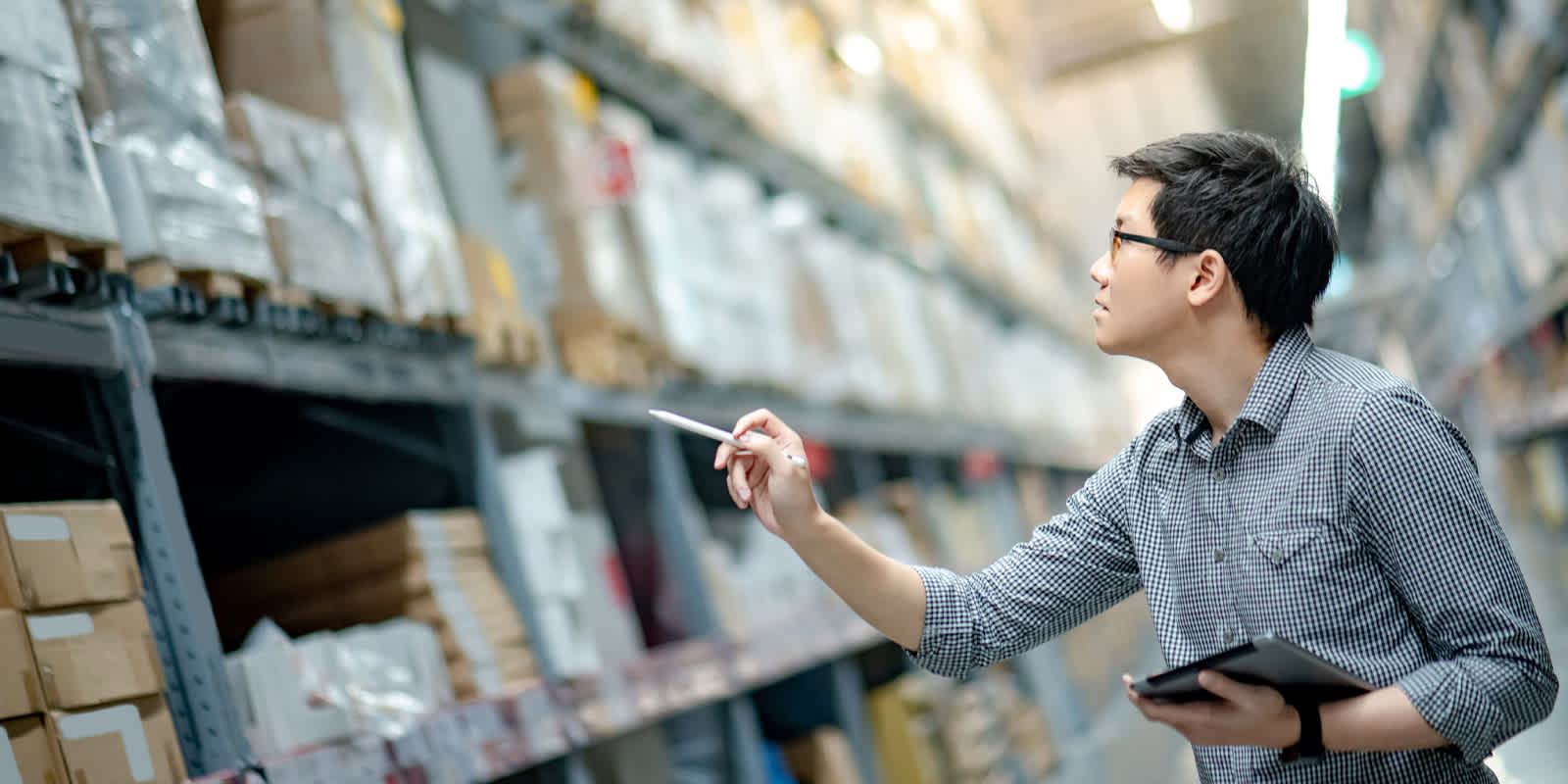 An admin worker counts packages in a warehouse. Image for masthead of Logistics Pressure Matrix report.