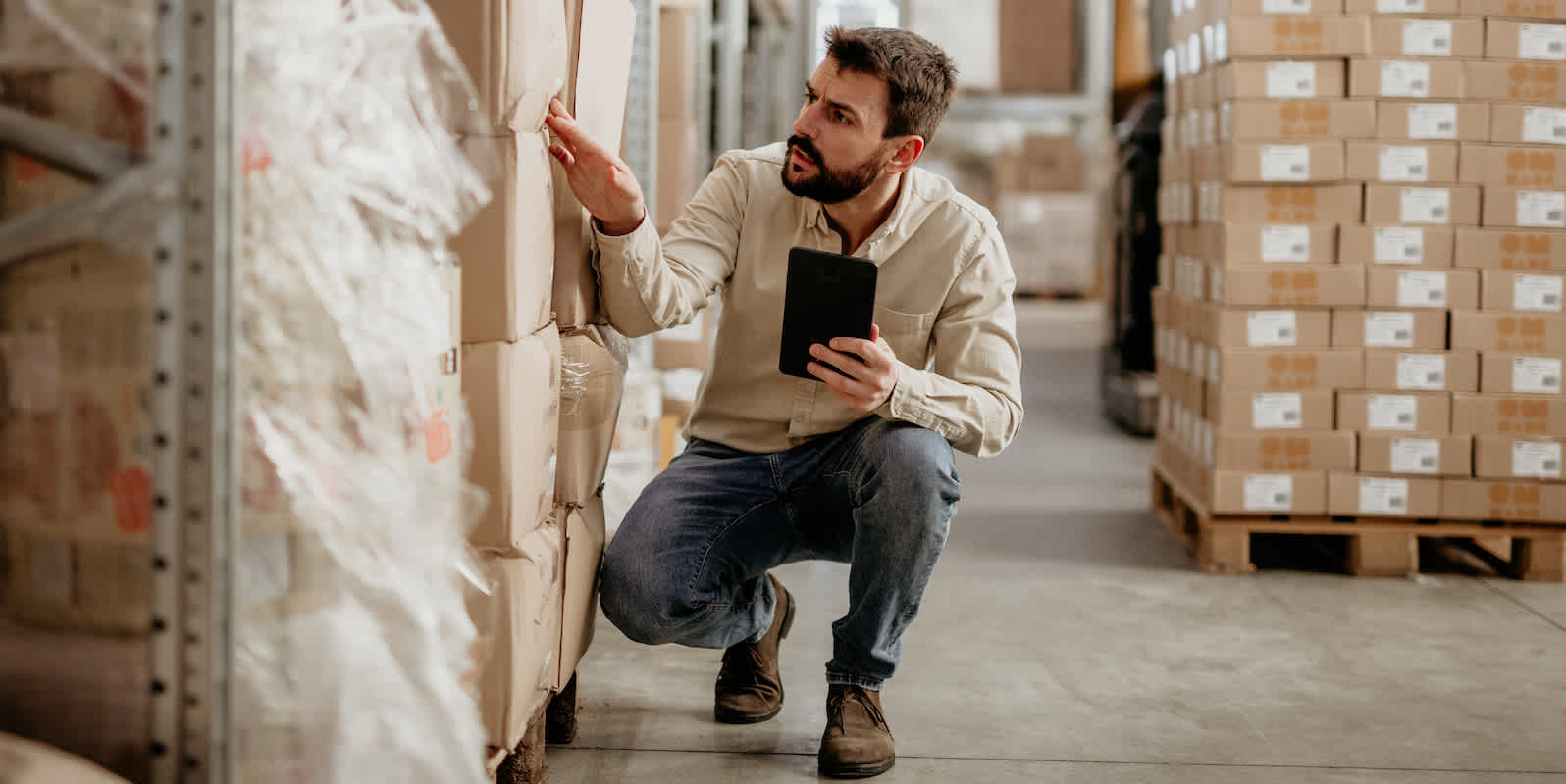 Man inspects a pallet of goods in a warehouse
