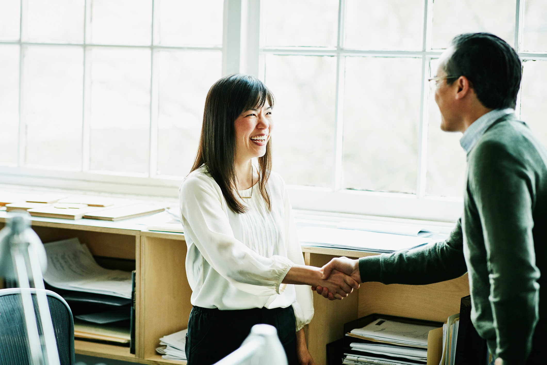 Business lady smiling shaking hands with smiling businessman