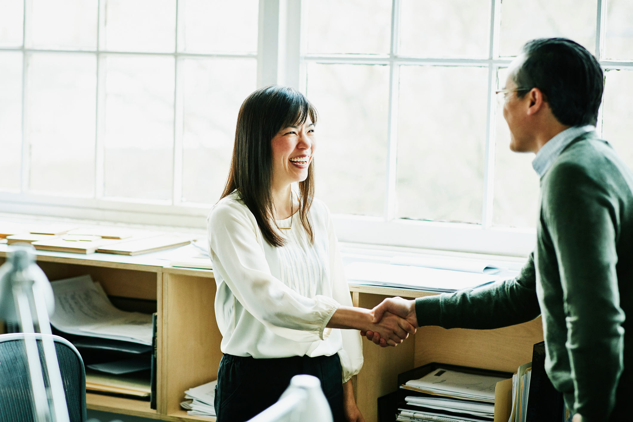 Business lady smiling shaking hands with smiling businessman