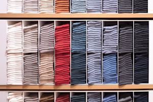 Neatly stacked and color-sorted clothing on retail display shelves