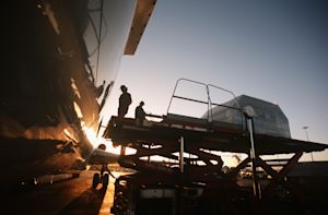 Ground crew loading air cargo onto a freighter aircraft at sunset