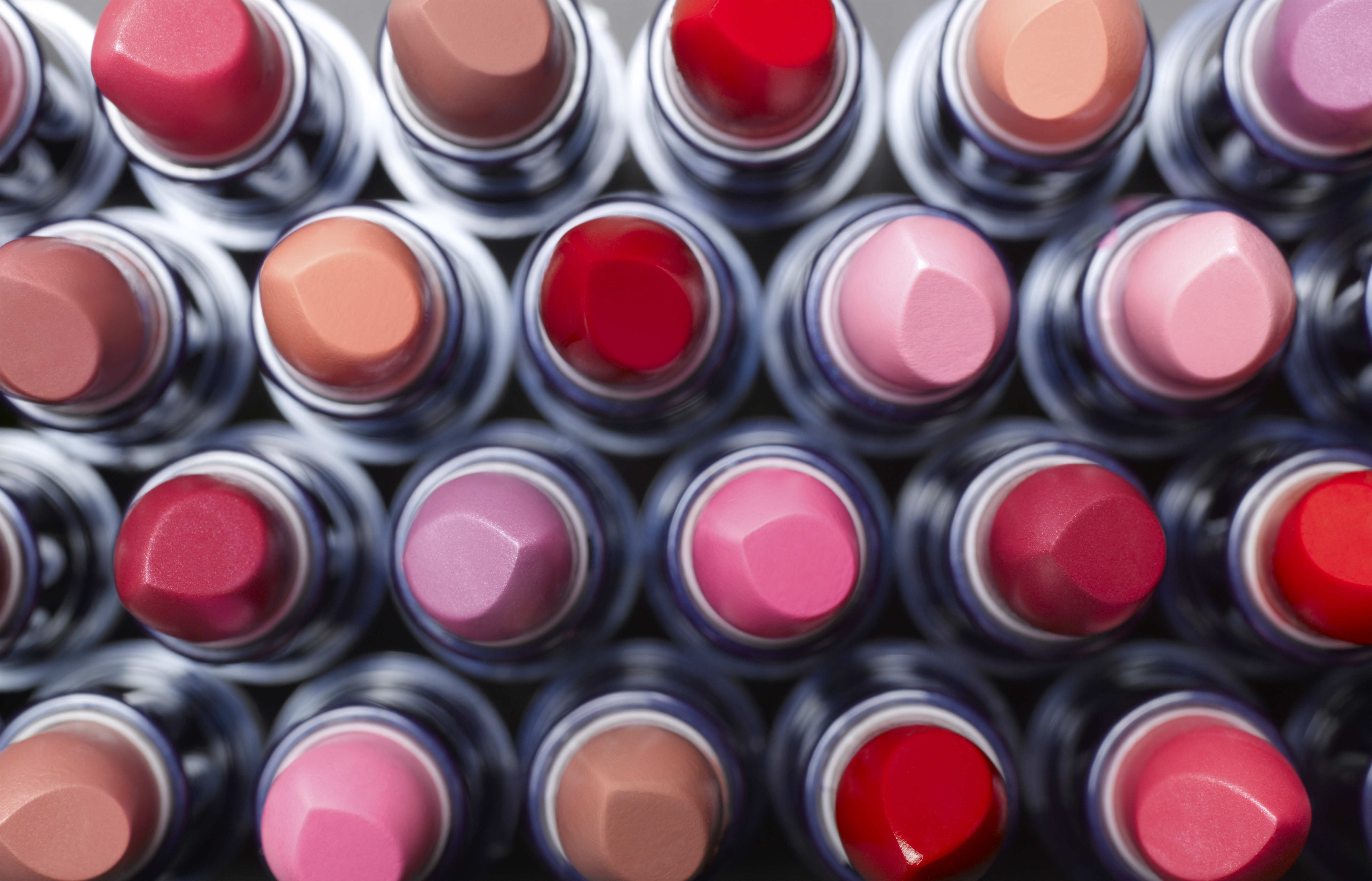 Overhead view of lipstick tubes arranged in rows of varied shades