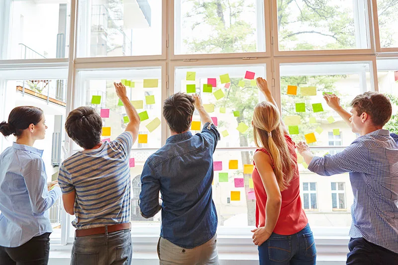 People putting sticky notes on a window