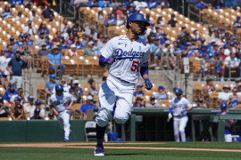 Los Angeles Dodgers right fielder Mookie Betts (50) runs to first base after hitting a single against the Chicago White Sox during the first inning of a spring training game at Camelback Ranch-Glendale. Mandatory Credit: Joe Camporeale-USA TODAY Sports.