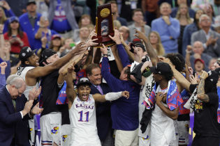 Kansas Jayhawks guard Remy Martin (11) celebrates as head coach Bill Self (middle right) helps lift the championship trophy after defeating the North Carolina Tar Heels during the 2022 NCAA men's basketball tournament Final Four championship game at Caesars Superdome. Mandatory Credit: Stephen Lew-USA TODAY Sports.