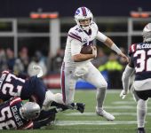 Bills quarterback Josh Allen (17) runs with the ball while evading tackles by New England Patriots defenders. / Bob DeChiara-USA TODAY Sports