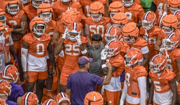 Clemson head coach Dabo Swinney talks with players on defense in orange and offense in white, during the first practice at Clemson, S.C. Friday, August 4, 2023.