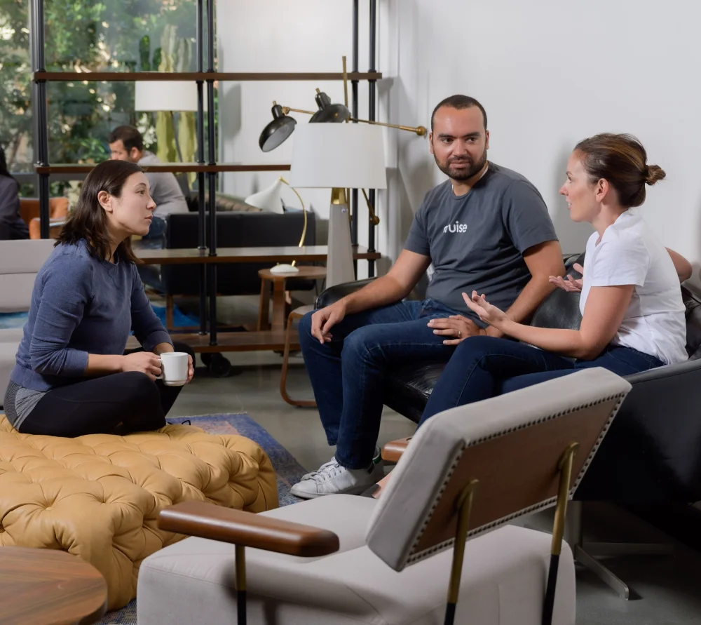 Employees sit together talking in a lounge area.