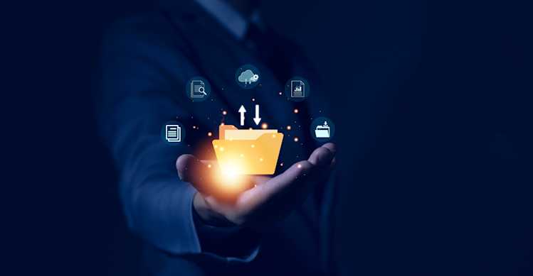 A person in a suit holds out their hand with a glowing digital folder surrounded by data and network-related icons. A person in a suit holds out their hand with a glowing digital folder surrounded by data and network-related icons.