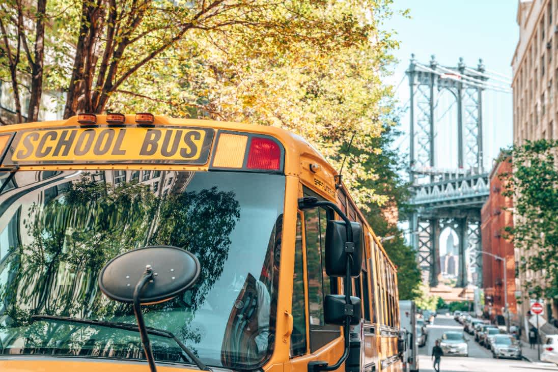 Image of a yellow school bus in the foreground of the Brooklyn Bridge Image of a yellow school bus in the foreground of the Brooklyn Bridge