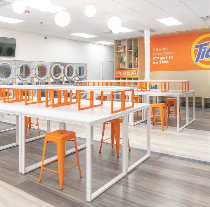 Lavandería Tide con muchos asientos y espacio ordenado.