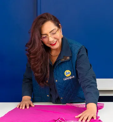 Empleado de Lavandería Tide revisando la ropa antes de lavarla.