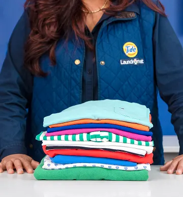Empleado de Lavandería Tide mostrando ropa doblada.