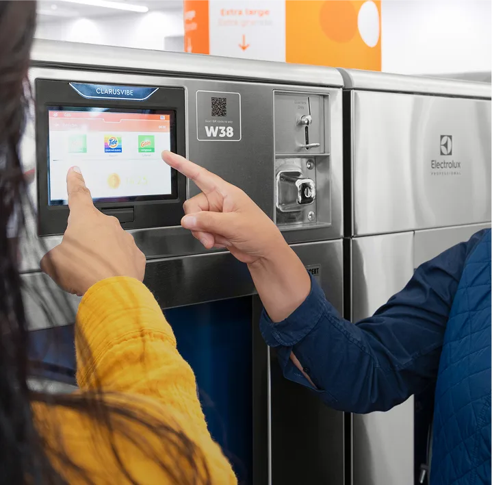 Empleado de Lavandería Tide ayudando a un cliente con la lavadora.