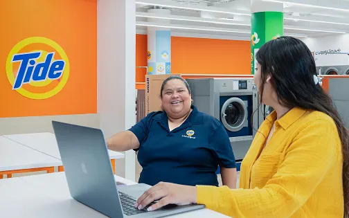 Dos personas sentadas en la lavandería Tide con aire acondicionado usando WiFi.