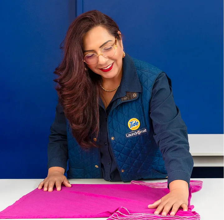 Empleado de Lavandería Tide revisando la ropa antes de lavarla.