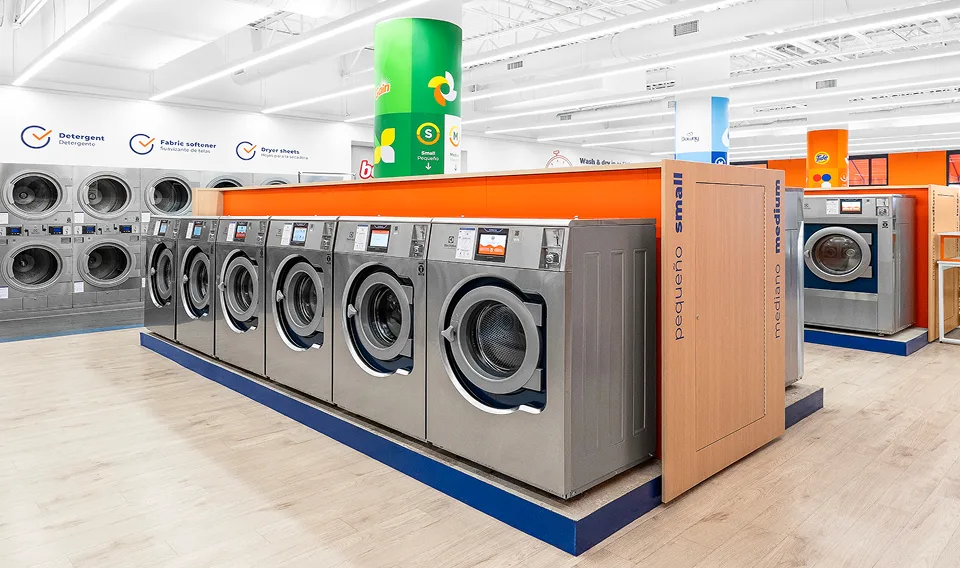 Fila de lavadoras y secadoras de Lavandería Tide listas para usar.