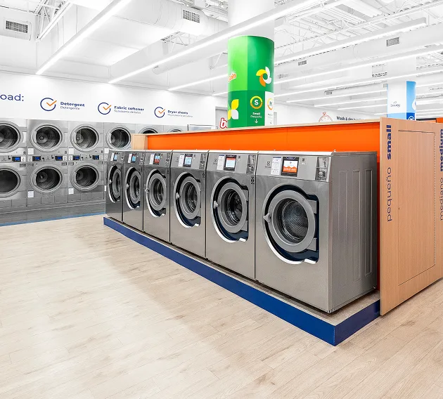 Fila de lavadoras y secadoras de Lavandería Tide listas para usar.