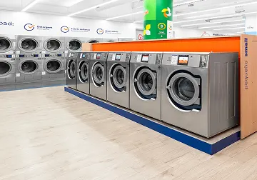 Fila de lavadoras y secadoras de Lavandería Tide listas para usar.