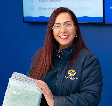 Empleado de Lavandería Tide mostrando toallas recién dobladas.