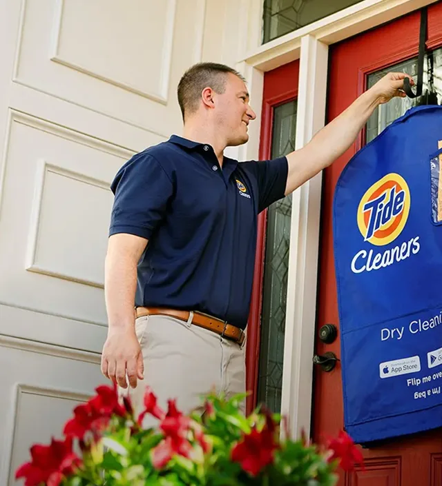 Empleado de Tide Cleaners entregando ropa limpia a domicilio.