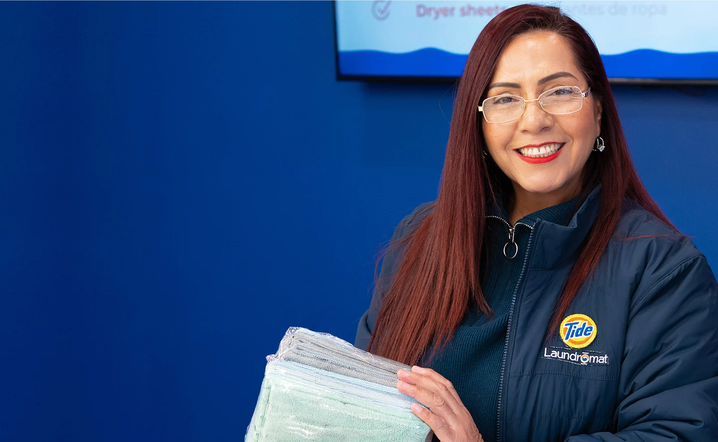 Empleado de Lavandería Tide mostrando toallas recién dobladas.