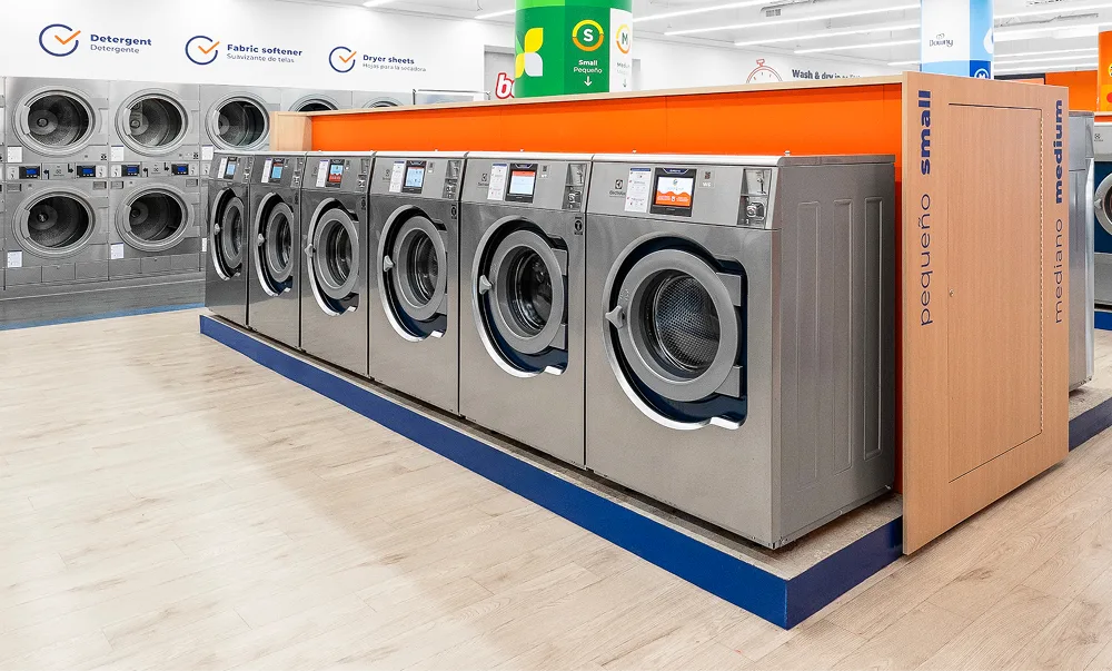 Fila de lavadoras y secadoras de Lavandería Tide listas para usar.