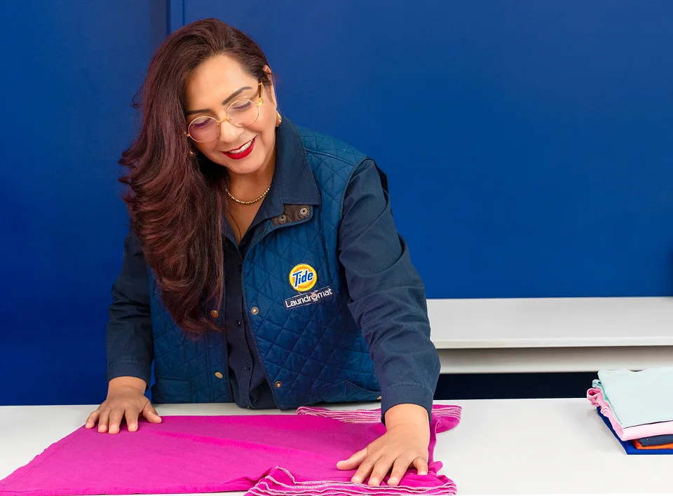 Empleado de Lavandería Tide revisando la ropa antes de lavarla.