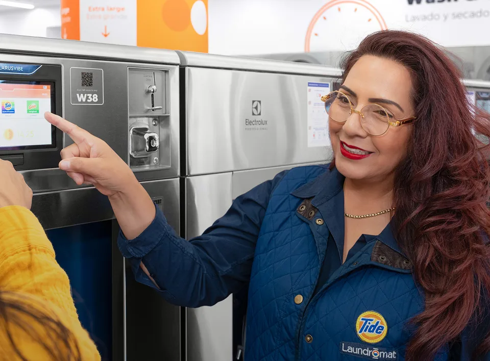 Empleado de Lavandería Tide ayudando a un cliente con la lavadora.
