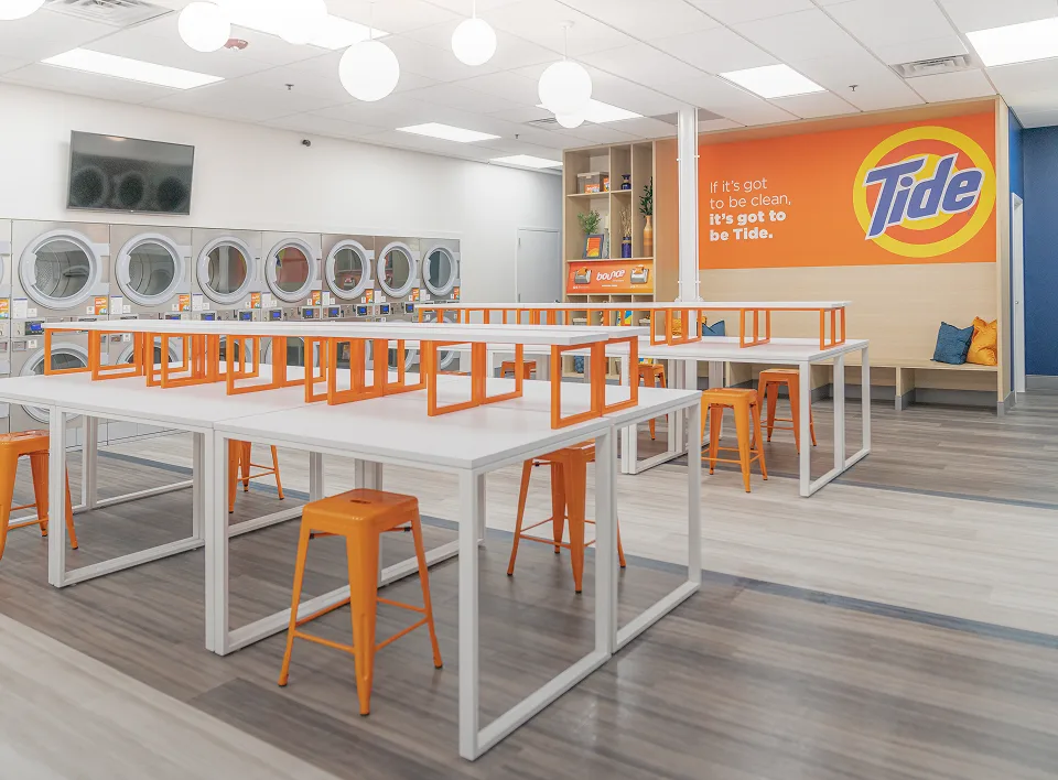 Lavandería Tide con muchos asientos y espacio ordenado.