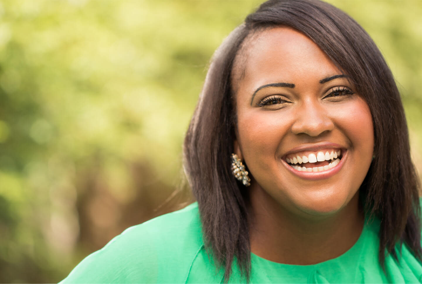 Smiling Black woman with relaxed hair in green shirt