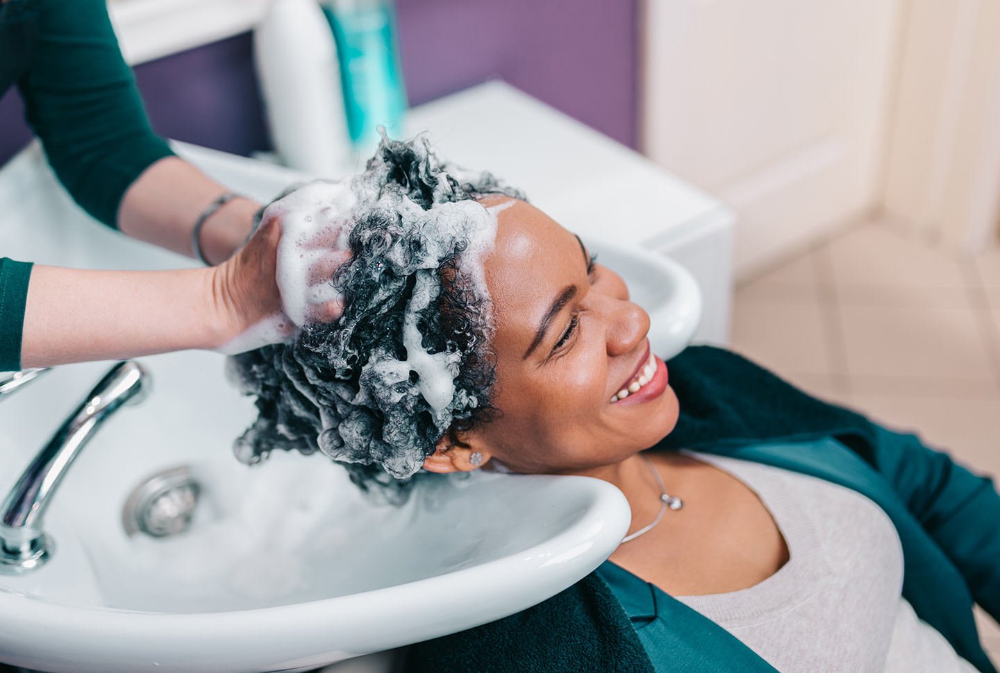 hairdresser washing the hair of an african-american woman in the seat of a hair salon hairdresser washing the hair of an african-american woman in the seat of a hair salon