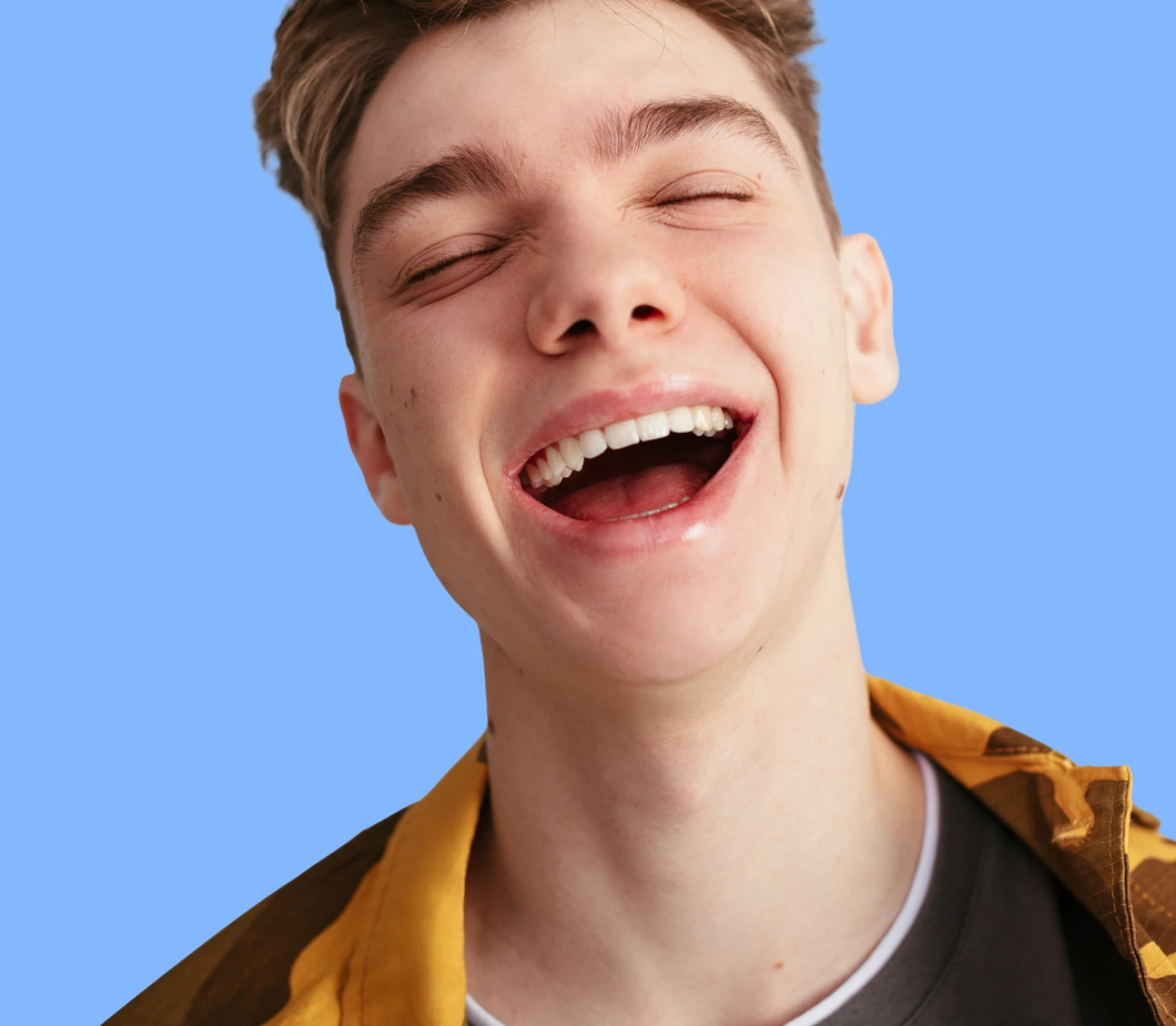 Teenage boy laughing with eyes closed
