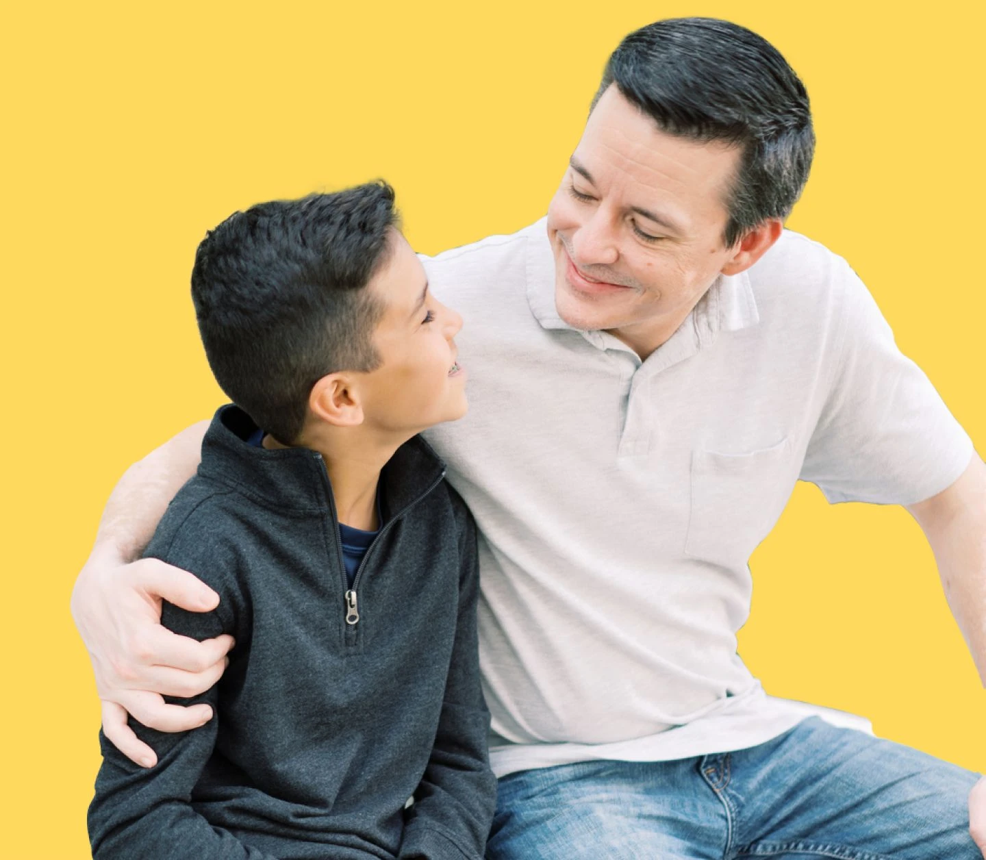 Dad hugging son with one arm as they sit side-by-side
