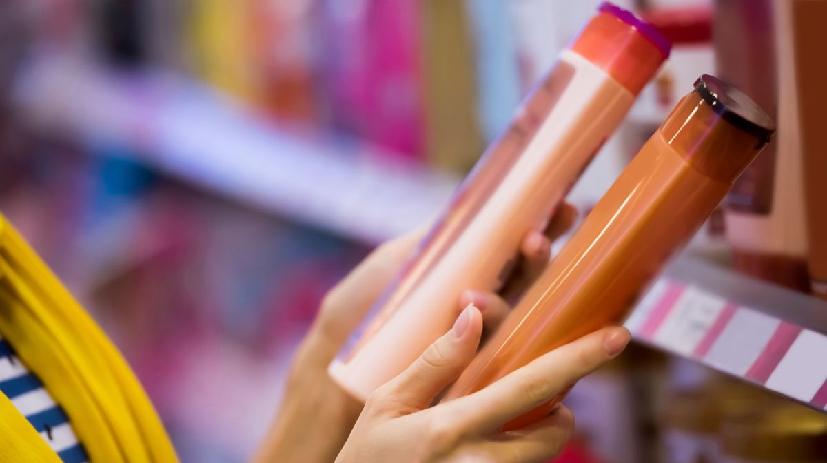 person examines shampoo packaging options at a store