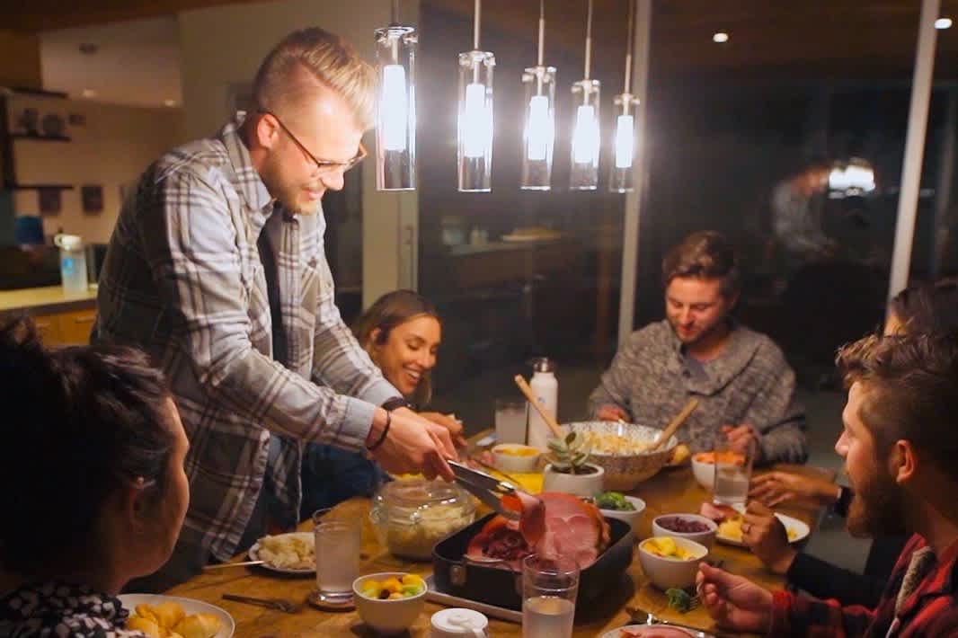 Young man serves his family at Thanksgiving dinner.