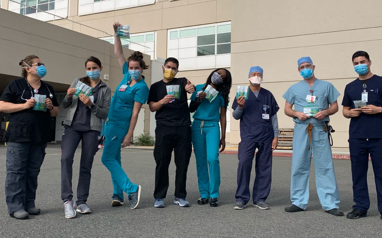 Six healthcare workers pose in front of hospital in scrubs while holding Liquid I.V. donations. 